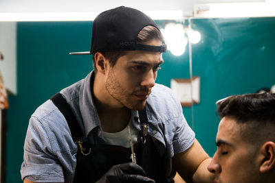 Barber looking at hair of man at salon