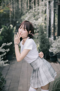 Side view of young woman standing against plants