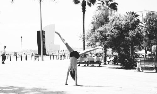 Full length of woman doing handstand on footpath