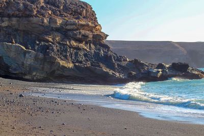 Scenic view of rocks on beach against sky