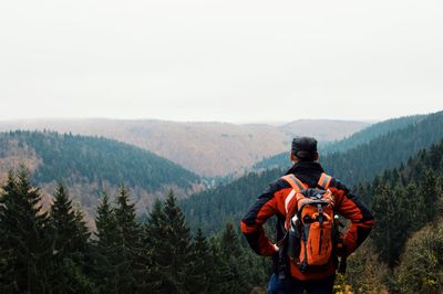 Rear view of man with backpack looking at mountains against sky