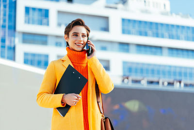 Young woman standing against building