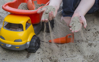 Cropped image of child playing with sand at beach