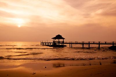 Silhouette lifeguard hut on beach against sky during sunset