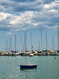 Sailboats moored in harbor against sky