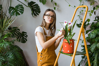 Young woman standing by potted plant