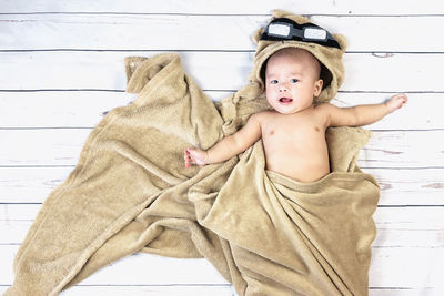 Portrait of cute baby boy lying on wooden floor