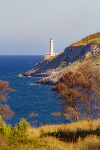 Lighthouse by sea against sky