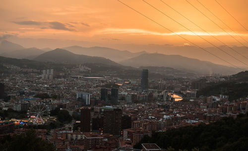 Aerial view of illuminated cityscape against sky during sunset