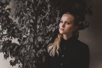 Beautiful young woman standing against wall