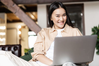 Portrait of young woman using laptop at home