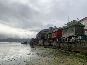 Houses by sea against sky in city