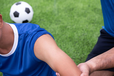 Midsection of man massaging hand on soccer field