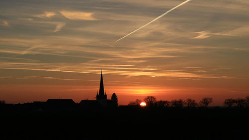 Silhouette built structure against orange sky