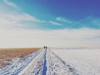 Tire tracks on field against sky