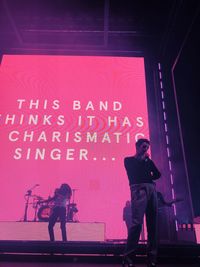 Full length of man standing against illuminated wall