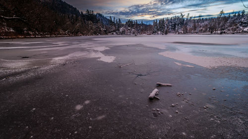 Snow covered landscape against sky during sunset