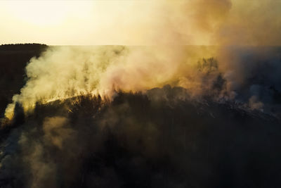 Smoke emitting from volcanic landscape against sky during sunset