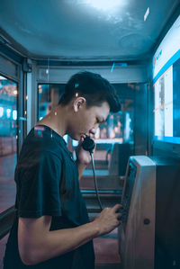 Side view of young man looking at camera