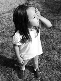 High angle view of girl covering her eye with hand while standing on field