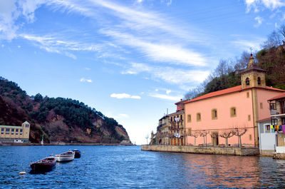 River amidst houses and buildings against sky