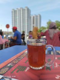 Close-up of beer in glass on table against buildings in city