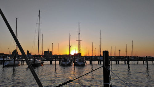 Sailboats in sea at sunset