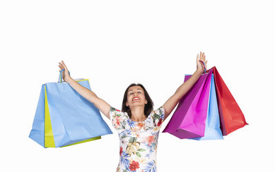 Smiling woman holding colorful shopping bags against white background