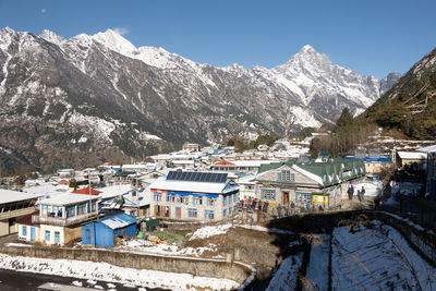 Houses by snowcapped mountains against sky