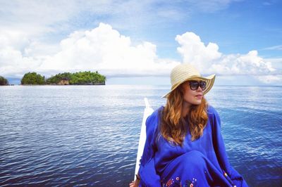 Beautiful young woman against sea against sky