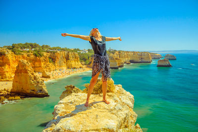 Woman with arms outstretched standing at beach