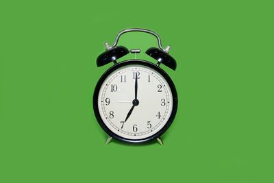 Close-up of alarm clock against green background