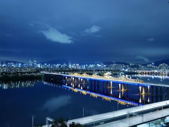 Illuminated bridge over river against sky at night