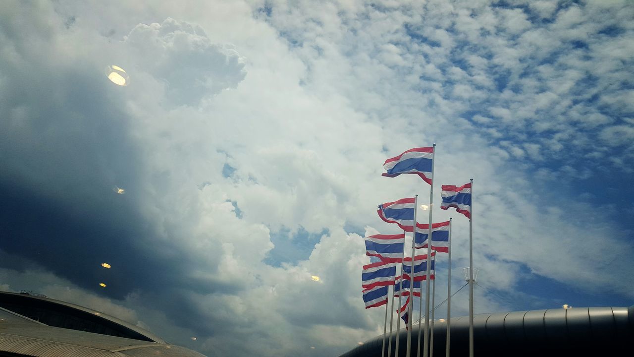 low angle view, sky, cloud - sky, flag, cloudy, patriotism, national flag, identity, american flag, cloud, weather, pole, overcast, day, outdoors, built structure, no people, street light, wind, culture