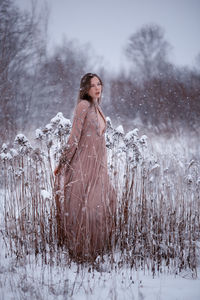 Woman standing on snow covered field