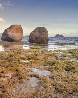 Rocks on beach against sky during sunset