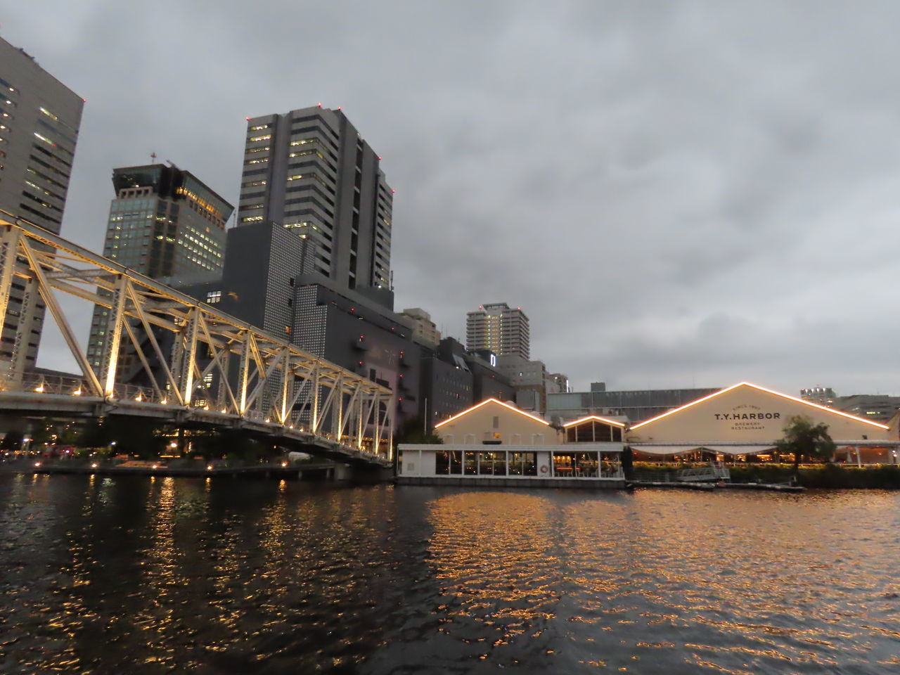 RIVER BY ILLUMINATED BUILDINGS AGAINST SKY IN CITY