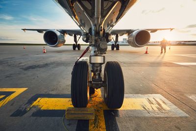 Airplane at airport runway against sky