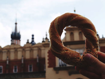 Close-up of hand holding pretzel against sky