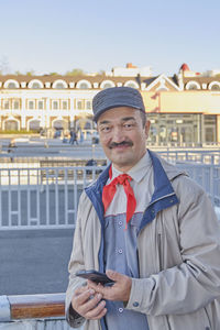 Senior asian man in red pioneer tie with mobile phone in hand. soviet holiday pioneer day.