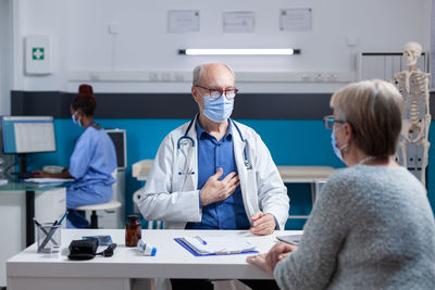 Doctor wearing mask examining patient in clinic