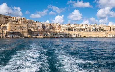 Buildings by sea against blue sky