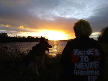 Rear view of dog on beach against sky during sunset