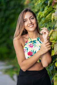 Portrait of smiling woman standing by plants outdoors