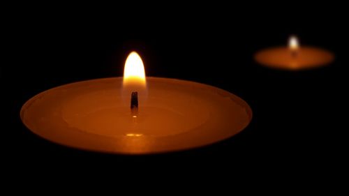 Close-up of lit tea light candle in darkroom