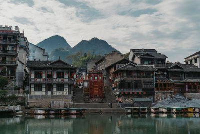 Buildings by river against sky