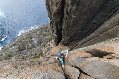 Female adventurer and rockclimber makes her way up the dolerite sea cliffs of cape raoul, tasmania, australia.