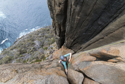 Rear view of man sitting on rock