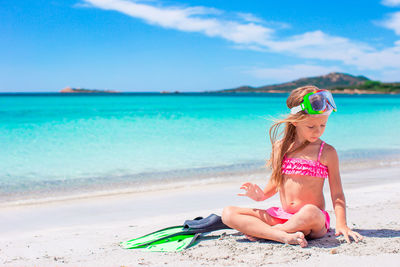 Full length of woman sitting at beach against sky