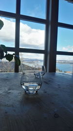 Close-up of table by sea against sky seen through window